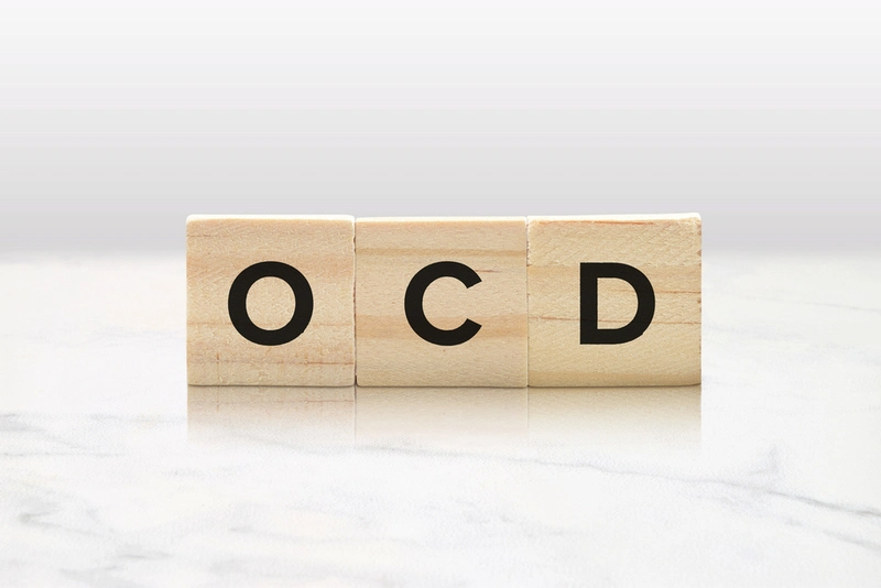 Three wooden tiles spelling OCD on a white background