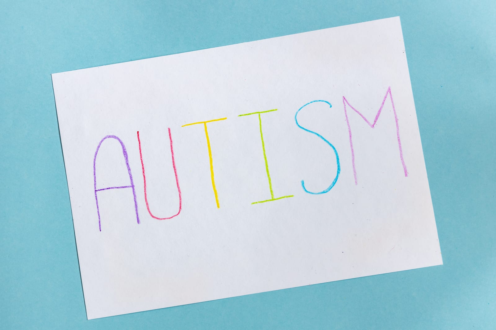 text word autism on paper sheet written by colorful letter on blue background