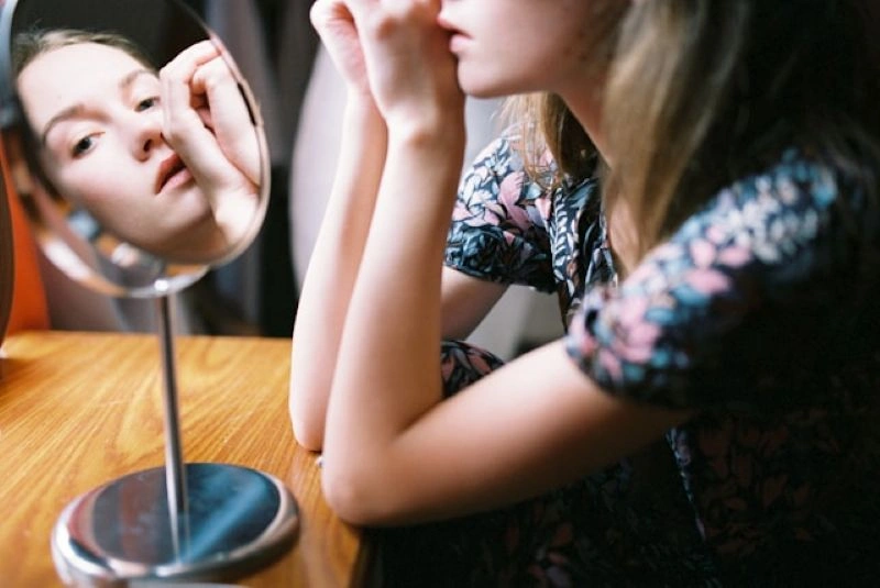 Teenager examining herself in a mirror, highlighting self-perception issues in anorexia nervosa vs bulimia nervosa