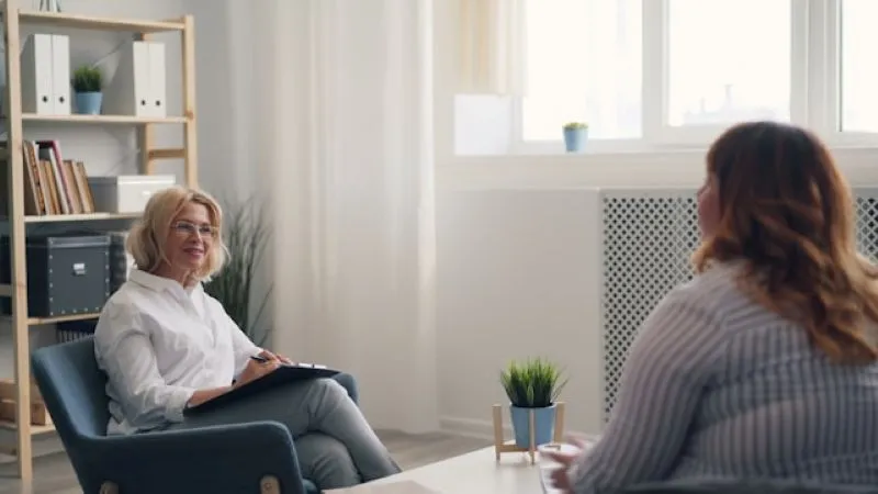 A patient discussing her condition with a female therapist in an office setting, demonstrating guidance from pmdd specialists.