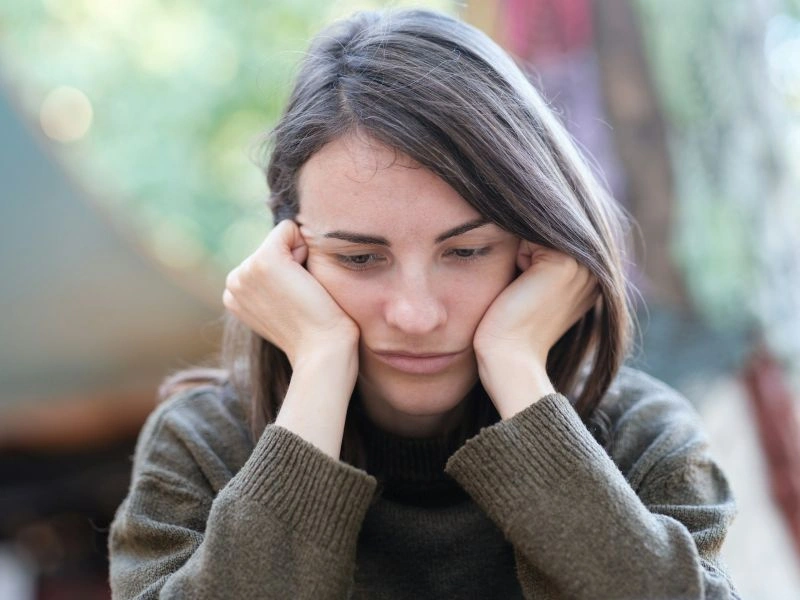 Woman sitting with a distressed expression, holding her head and looking down, reflecting concern and uncertainty about can an antidepressant stop working during treatment.