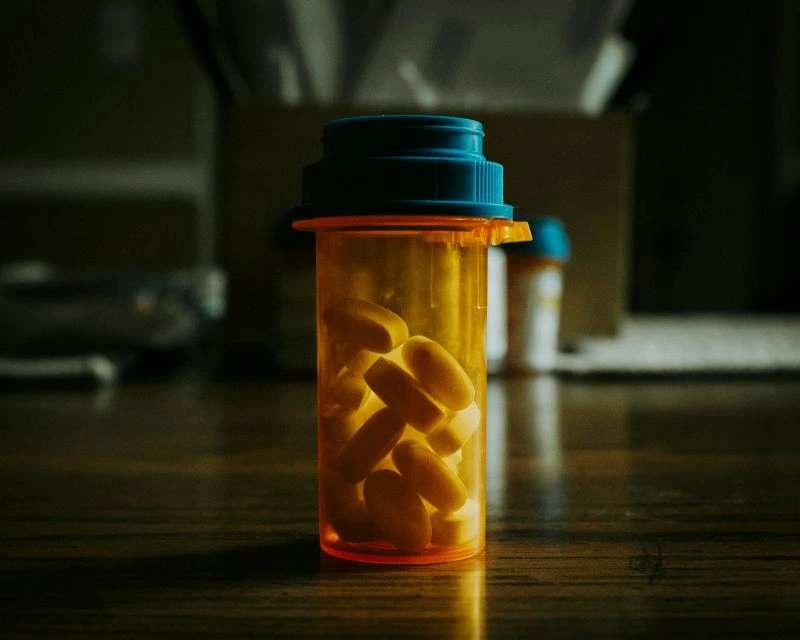 Orange prescription pill bottle on a dark surface with capsules inside, symbolizing medication management and questions like can an antidepressant stop working over time.