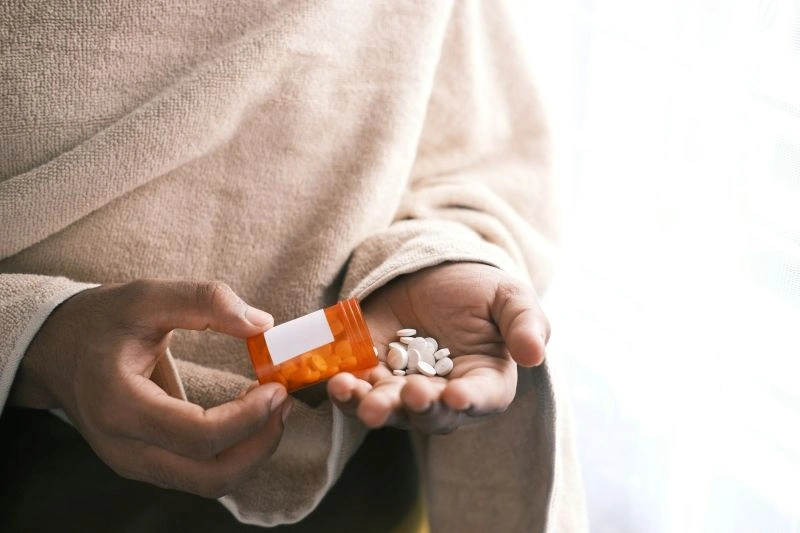 Hands holding a small container of pills spilling into the palm, illustrating changes in medication response and concerns around can an antidepressant stop working.