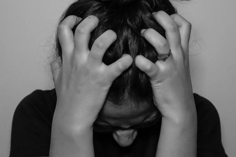 Black-and-white image of a person clutching their head in visible emotional strain, symbolizing severe signs depression is getting worse.