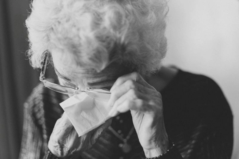Anxiety in the elderly represented by an older person wiping tears, showing emotional distress and feelings of worry.