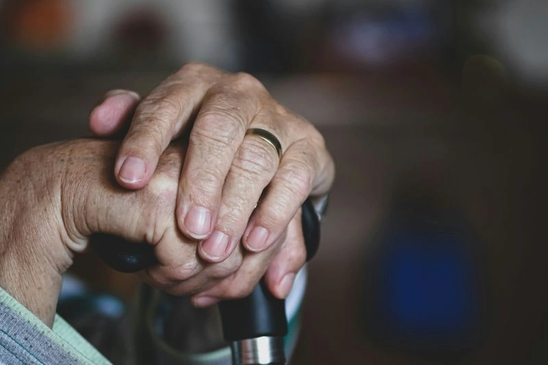 Anxiety in the elderly depicted through a close-up of an elderly person holding a cane, reflecting concerns and emotional challenges in later life.