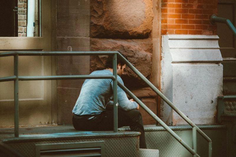 Fear of failure illustrated by a person sitting alone outside, reflecting on uncertainty and personal struggles.