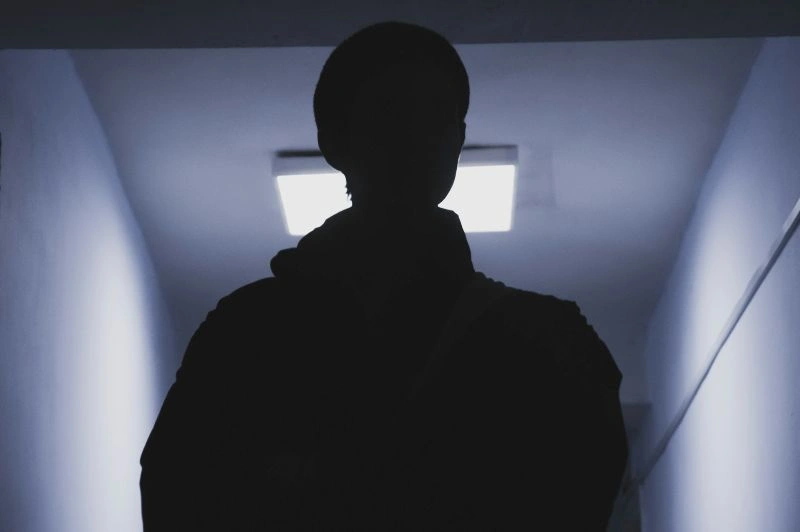 Hypervigilance in anxiety represented by a person standing in a dim hallway, reflecting heightened alertness and constant awareness of surroundings.