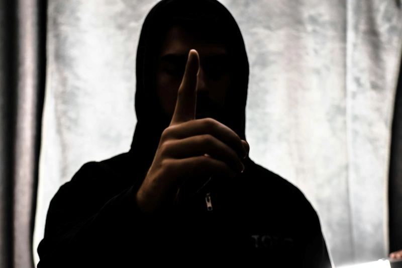 Hypervigilance in anxiety depicted by a person in a dark setting with a hand gesture, symbolizing fear, caution, and increased sensitivity to threats.