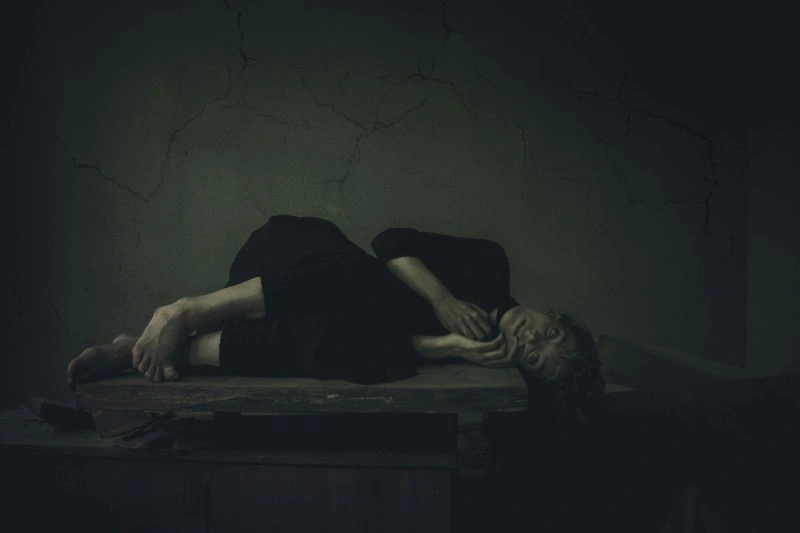 Nocturnal anxiety depicted by a person lying awake in a dark room, showing distress and restless thoughts at night.