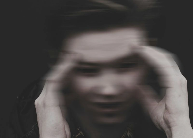 Nocturnal anxiety illustrated by a blurred face and hands holding the head, representing overwhelming nighttime worries.
