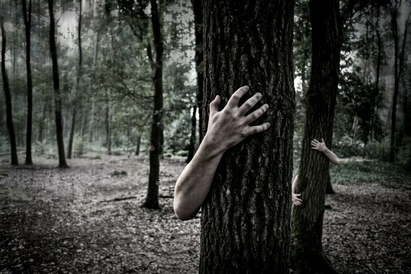 Nocturnal anxiety symbolized by a person hiding behind a tree in a dark forest, reflecting fear and unease during the night.