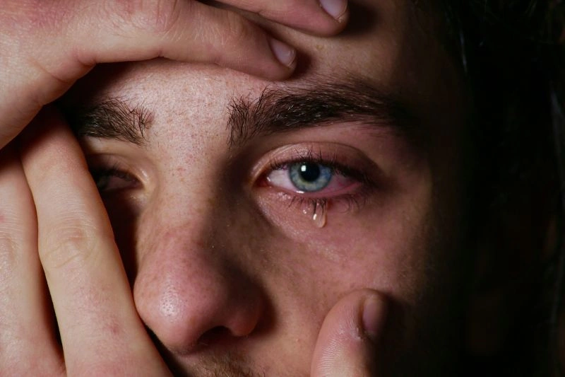 Extreme close-up of a man’s face with a tear in his eye, showing quiet distress and disconnection commonly associated with emotional numbness.