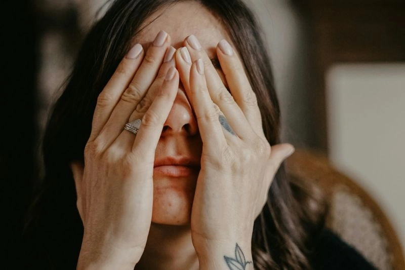 Close-up of a woman covering her face with both hands in distress, illustrating feelings of emotional numbness and internal emotional shutdown.