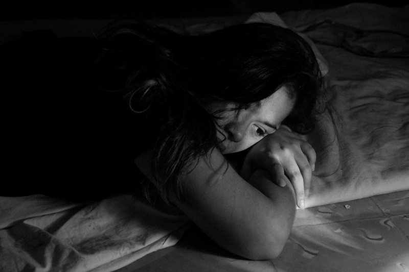 1. Woman lying awake in bed with a distressed expression, showing persistent low mood and emotional exhaustion associated with depression vs sadness.