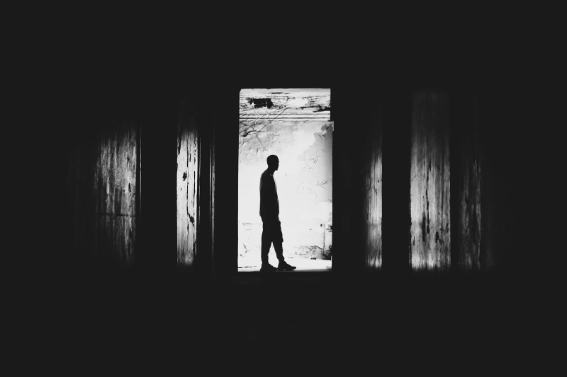 Silhouette of a person standing alone in a dark doorway, reflecting isolation, uncertainty, and persistent doubt connected with false memory OCD.