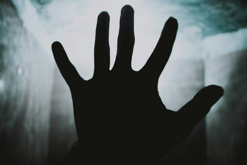 Silhouetted hand reaching forward in a dark, misty setting, symbolizing intrusive thoughts and distress associated with OCD fear of death.