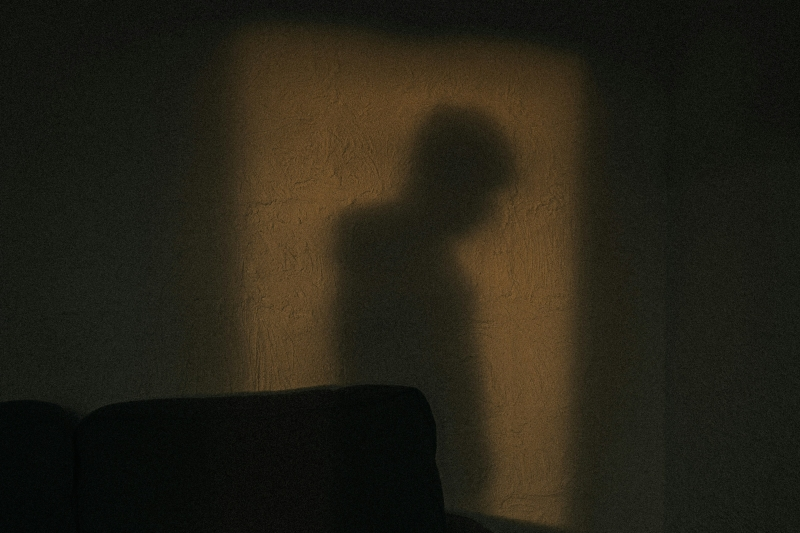 Shadow of a person cast against a dim wall, representing isolation, rumination, and anxiety linked to OCD fear of death.