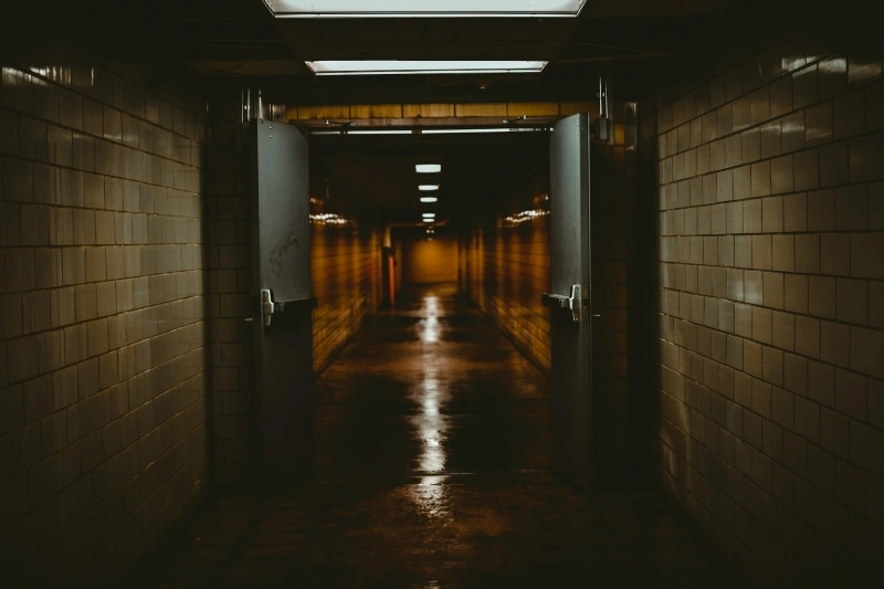 Dark empty hallway with open doors and low lighting, reflecting uncertainty and persistent thoughts connected with OCD fear of death.
