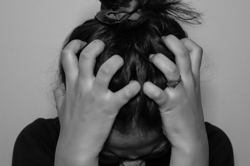 Black-and-white close-up of a distressed woman holding her head, representing intense anxiety and the search for how to heal anxiety without medication.