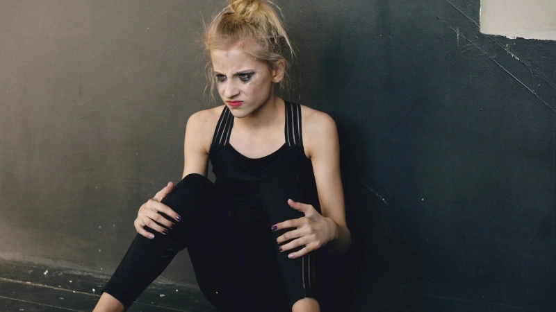 Teen girl sitting alone with a distressed expression, reflecting emotional struggles that may lead families to seek depression treatment for teenager.